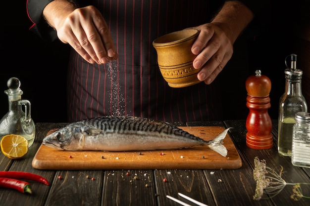 Szef kuchni rybnej przygotowuje w kuchni świeżą makrelę Scomber musi być solony przed pieczeniem kuchni europejskiej