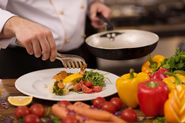 szef kuchni serwujący sałatkę jarzynową na talerzu w kuchni restauracji