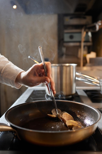 Szef Kuchni Smażący Małże W Komercyjnej Kuchni W Restauracji Zbliżenie Na Rękach