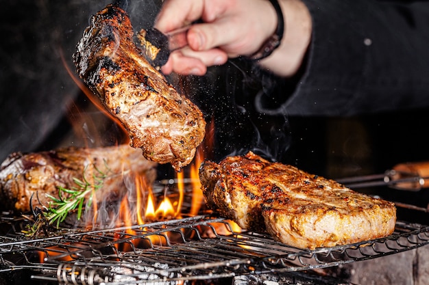 Szef kuchni smaży mięso, stek wołowy na otwartym ogniu w restauracji