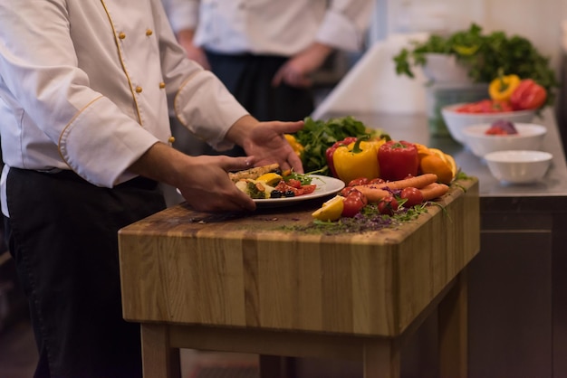 Szef kuchni trzymający smażony filet z łososia z warzywami na obiad w kuchni restauracji