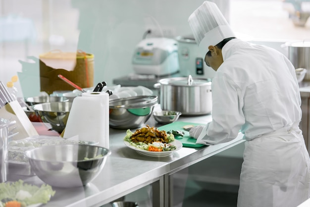 Szef Kuchni W Białym Mundurze Szefa Kuchni Gotuje W Kuchni, Aby Podawać Jedzenie Klientom W Hotelowej Restauracji