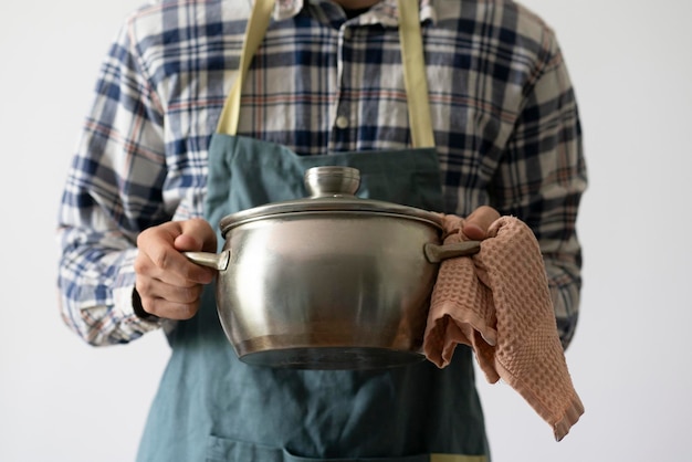 Szef kuchni w fartuchu naczynie do gotowania trzyma garnek w kuchni