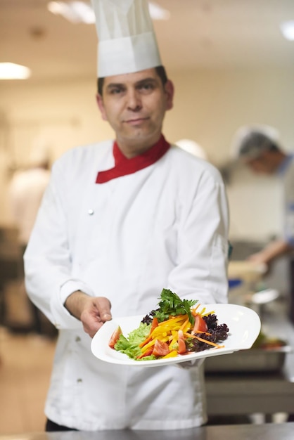 szef kuchni w hotelowej kuchni przygotowujący i dekorujący jedzenie, pyszne warzywa i obiad mięsny