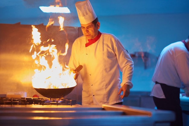 szef kuchni w kuchni hotelowej przygotowuje potrawy warzywne z ogniem
