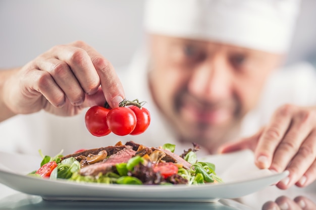 Szef kuchni w kuchni hotelu lub restauracji dekoruje jedzenie tuż przed podaniem.