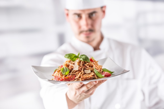 Zdjęcie szef kuchni w restauracji kuchnia trzymając talerz z włoskim posiłkiem spaghetti bolognese.