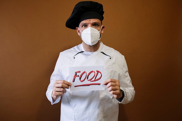Szef kuchni z maską i tabliczką z napisem: jedzenie
