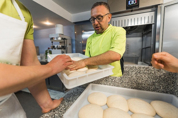 Zdjęcie szef pizzerii przygotowuje ciasto do pizzy w restauracji