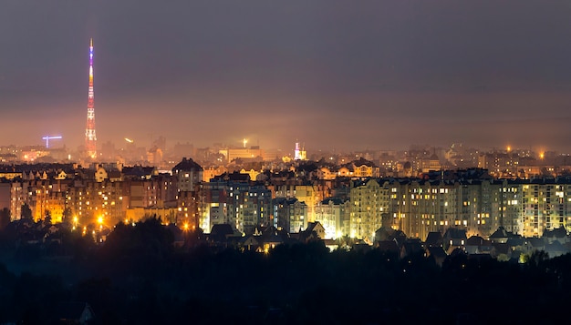 Szeroka panorama, widok z lotu ptaka w nocy nowoczesne miasto Iwano-Frankowsk, Ukraina. Scena jasnych świateł wysokich budynków, wysokiej wieży telewizyjnej i zielonych przedmieść.