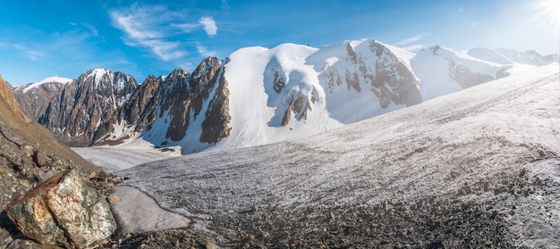 Szeroka panorama wielkiego lodowca, wysoko w górach, pokryta śniegiem i lodem.