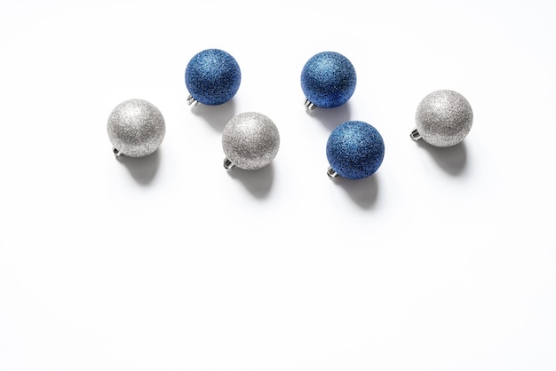 Sześć błyszczących bombek w kolorze srebrnym i niebieskim na białym tle z miejsca na kopię