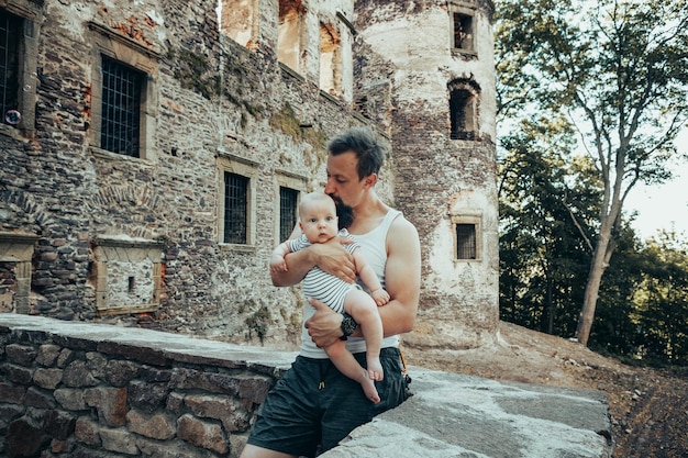 Sześciomiesięczne dziecko w ramionach ojca na tle starego zamku