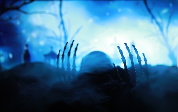 Zdjęcie szkielet zombie ręka wyrasta z cmentarza - halloween. tajemnicze prognozy magicznej kuli i dym na ciemnej scenie. wróżka, siła umysłu, koncepcja przewidywania. tajemnicze tło