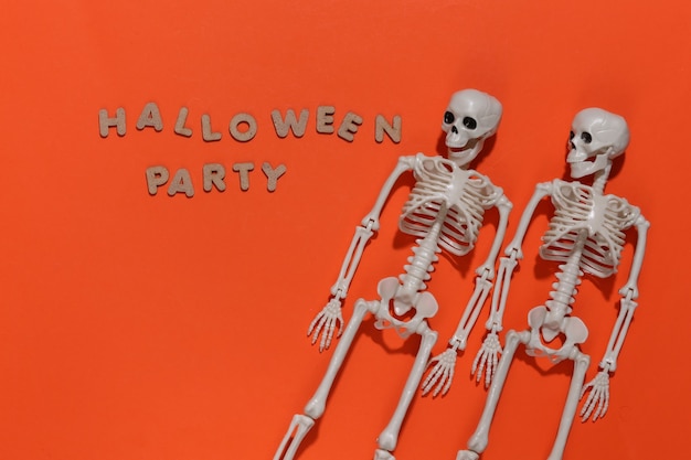 Szkielety na jasnym pomarańczowym tle z napisem Halloween party. Motyw Halloween.