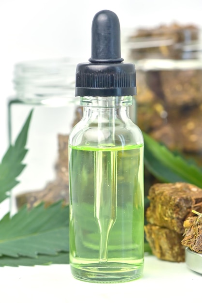 Zdjęcie szklana butelka oleju z konopi indyjskich i słoik suszonych konopi na białym tle cbd olej konopny olej konopny medyczne produkty marihuany, w tym liść konopi cbd i olej haszyszowy medycyna alternatywna