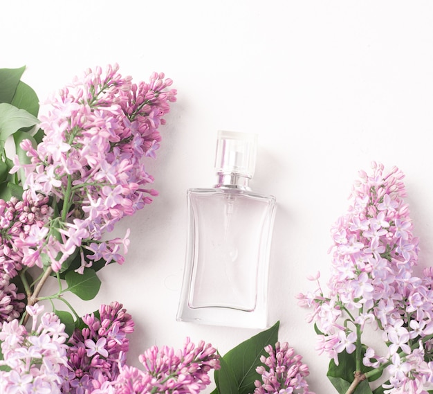Szklana butelka perfum i kwiatów bzu na białym tle