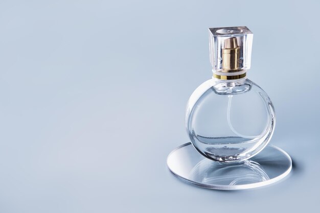 Szklana butelka perfum i okrągłe slajdy na niebieskim tle Zimowy lub wiosenny kwiatowy zapach