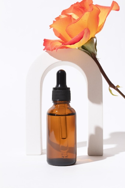 Szklana butelka z serum w łuku z kwiatem róży Serum z kwasem hialuronowym z kolagenem i peptydami Produkt do pielęgnacji skóry Opakowanie makiety Projektowanie kosmetyków branding