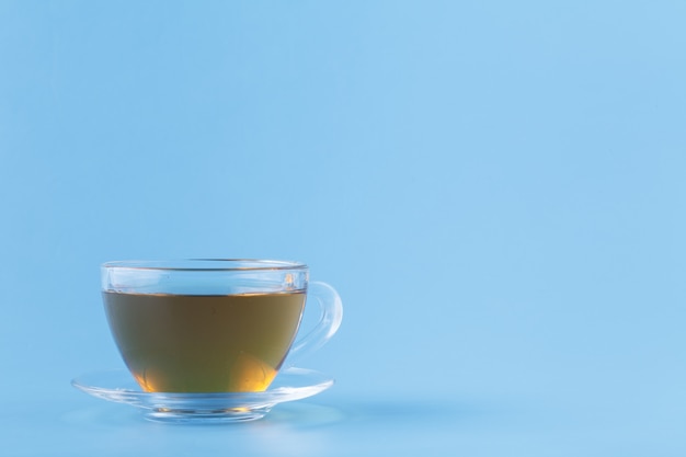 Szklana filiżanka z ziołową herbatą na błękitnym tle