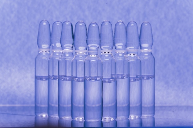 Szklana fiolka medyczna z ampułką do wstrzykiwań Lek jest płynnym chlorkiem sodu z wodnym roztworem w ampułce Zbliżenie Butelki ampułki wielokolorowe