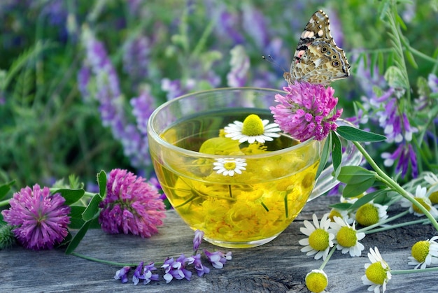 szklana miska z żółtym płynem z motylem i fioletowymi kwiatami