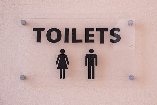 Zdjęcie szklana tabliczka z napisem wc dla kobiet i mężczyzn. znak toalety publicznej w hotelu?