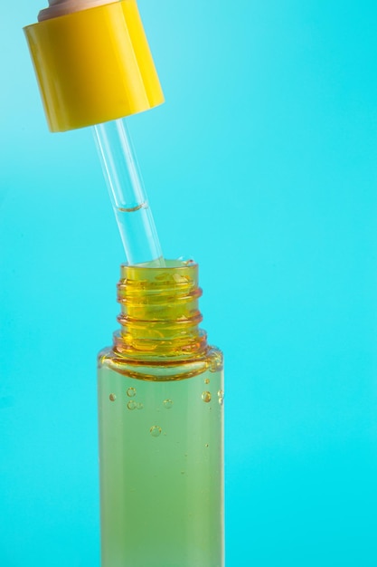 Szklana żółta butelka z pipetą z olejkiem eterycznym na niebieskim tle widok z góry Kosmetyk aromatyczny