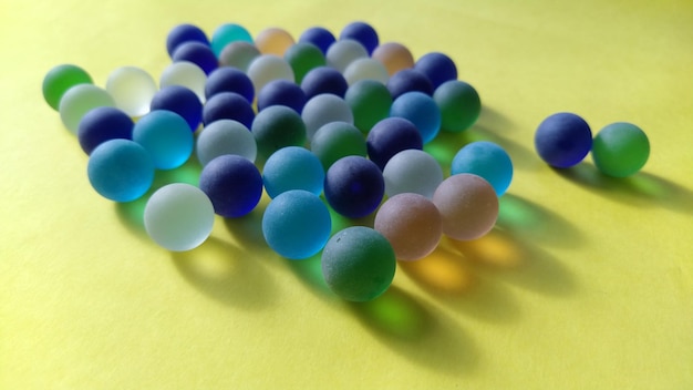 Szklane kulki w różnych kolorach leżą na żółtej powierzchni 2 kulki są przeciwko wszystkim innym