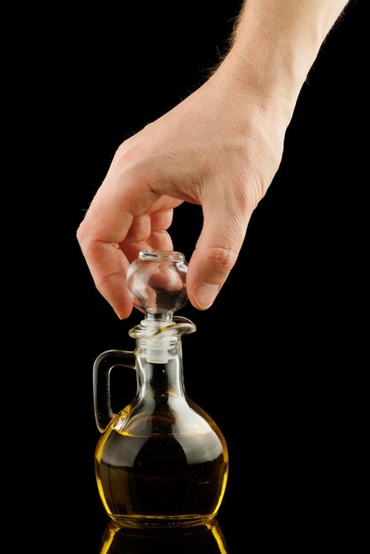 Szklane naczynie z olejem w ręku izolat
