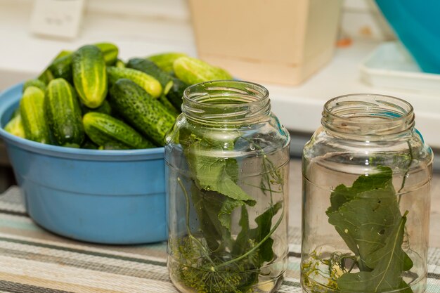 Szklane słoiki na stole z ziołami do konserwowania ogórków.