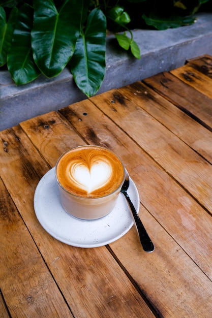 Szklanka cappuccino na drewnianym tle z piękną sztuką latte koncepcji miłości w kształcie serca