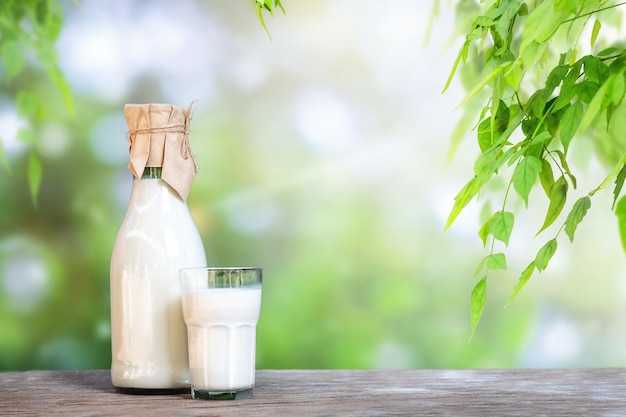 Szklanka i butelka z mlekiem na drewnianej powierzchni w naturze