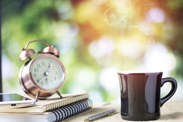 szklanka kawy na stole z książką i zegarem rano