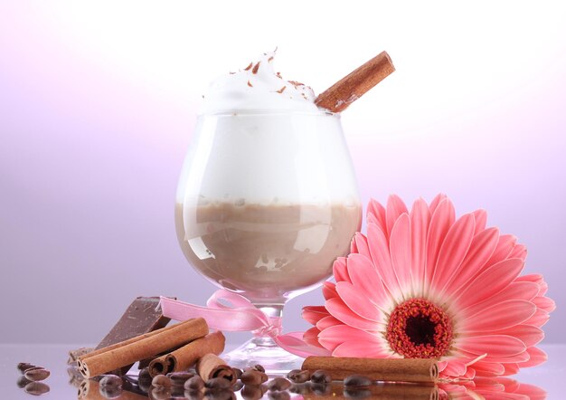 Szklanka koktajlu kawowego i kwiat gerbery na fioletowym tle