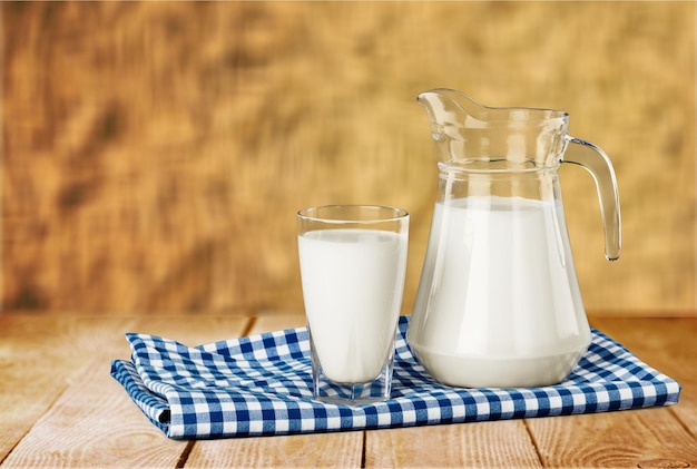 Zdjęcie szklanka mleka i dzbanek na drewnianym stole