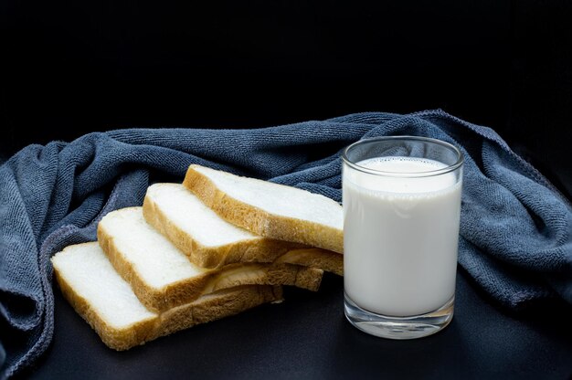 Szklanka mleka i krojonego chleba na śniadanie na czarnym tle obrazu żywności i zdrowej koncepcji