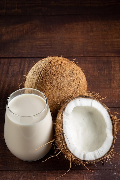 Szklanka mleka kokosowego z kawałkami kokosa na stole