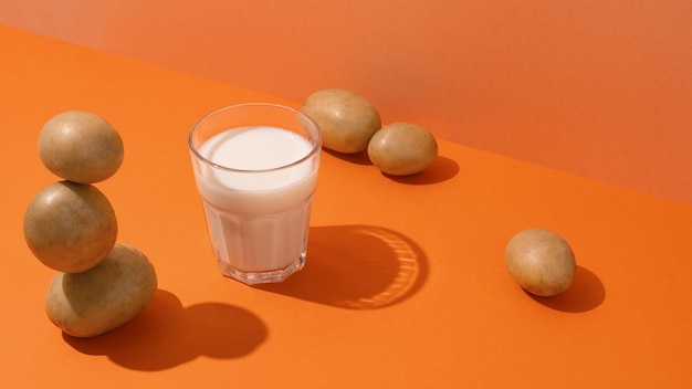Szklanka mleka ziemniaczanego na stole z ziemniakami