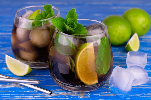 Szklanka mojito z lodem i limonkami na niebieskim drewnianym stole