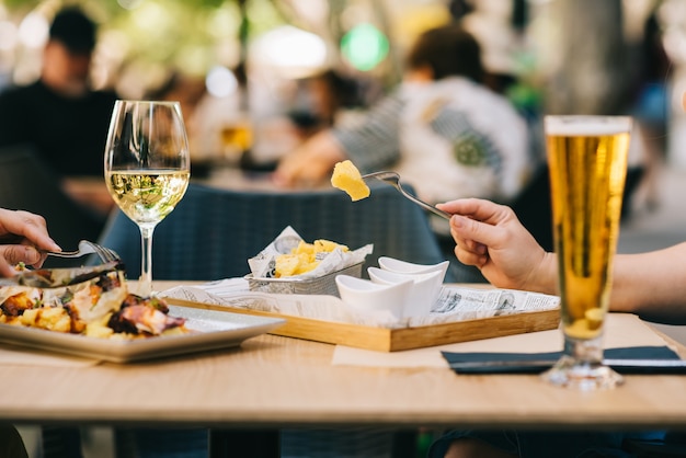 Zdjęcie szklanka piwa i wina na stole, jedzenie na tarasie - dwie dziewczyny jedzą razem obiad w restauracji