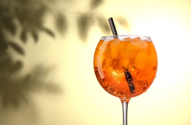 Szklanka pomarańczowego koktajlu aperol spritz na nieostrym tle liści