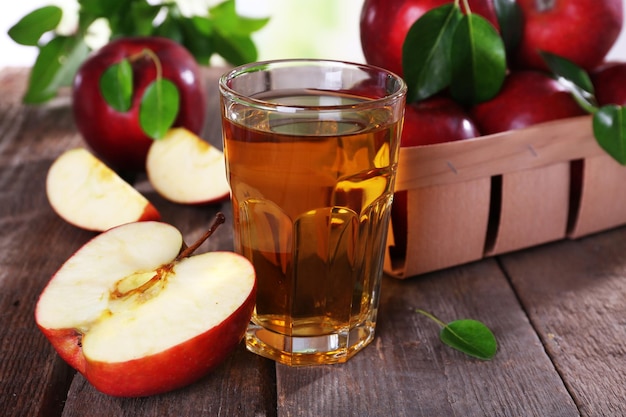 Szklanka soku jabłkowego z czerwonymi jabłkami na drewnianym stołowym zbliżeniu