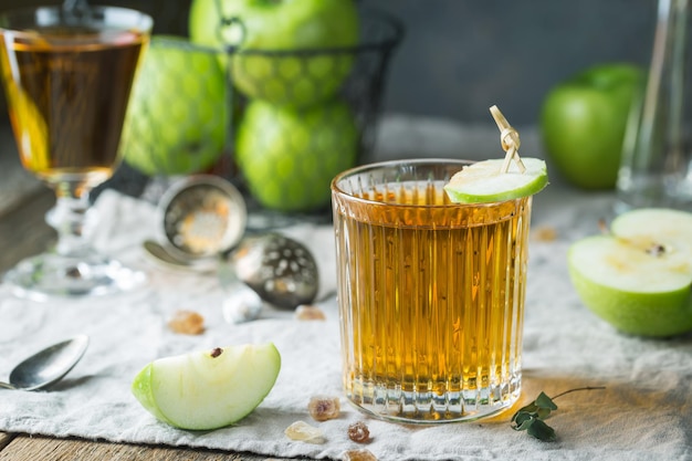 Szklanka soku jabłkowego z zielonymi jabłkami na drewnianym stole, w stylu rustykalnym