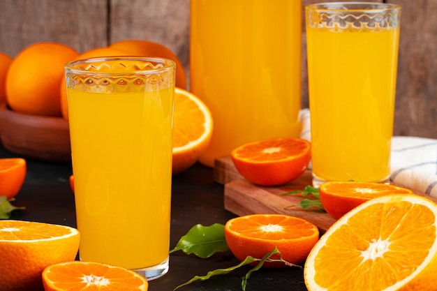 Zdjęcie szklanka soku pomarańczowego i pokrojone pomarańcze na stole