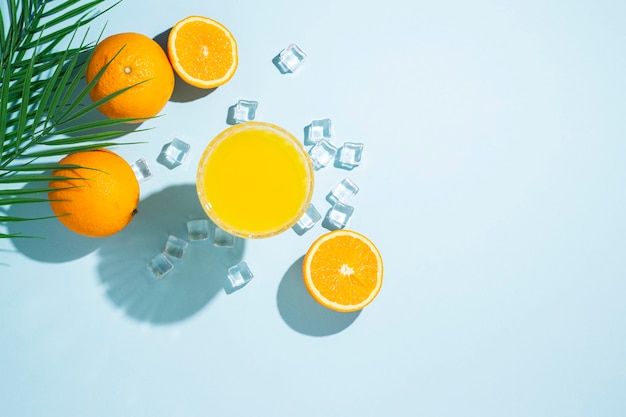 Szklanka soku pomarańczowego, pomarańczy i kostek lodu
