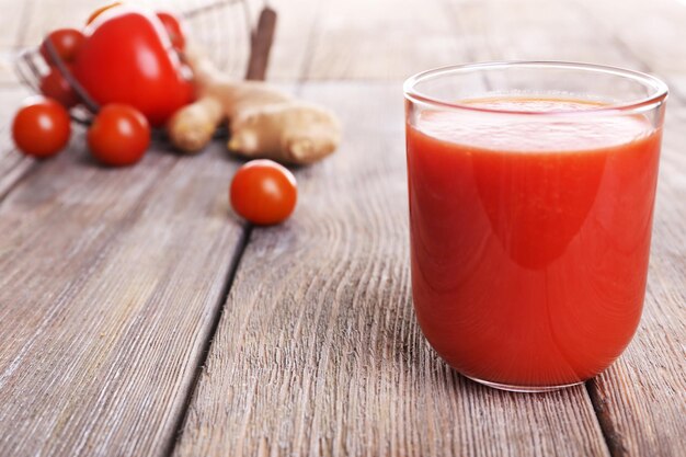 Szklanka soku pomidorowego z pomidorkami koktajlowymi na drewnianym stole z bliska