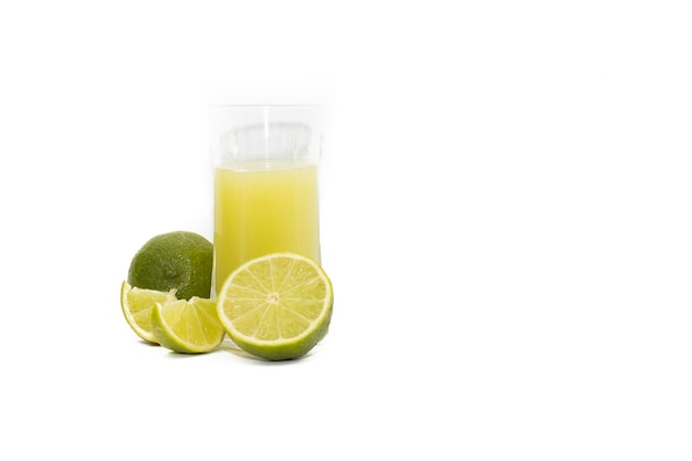 Szklanka soku z limonki i pokrojone w plasterki owoce limonki na białym tle