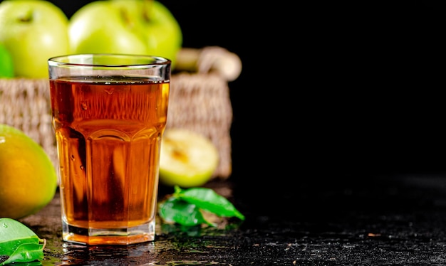Szklanka soku z zielonego jabłka z liśćmi na stole