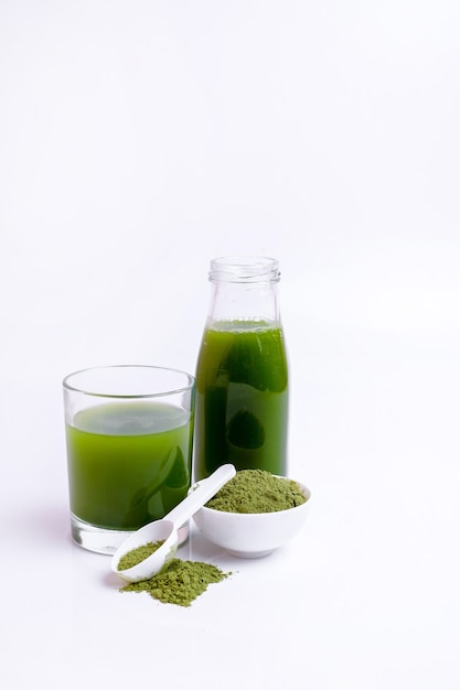 Szklanka soku z zielonych warzyw i proszku z warzyw na łyżce na białej powierzchni